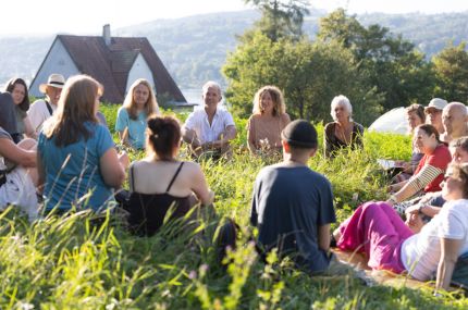 Eine Gruppe von Pioneers.Members sitzen auf grüner Wiese
